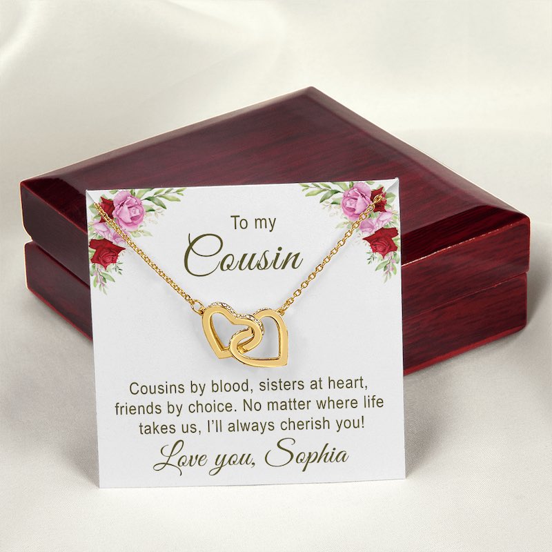 Gold necklace with interlocking hearts on a card with floral design and sentimental message for cousin, placed in a wooden box.
