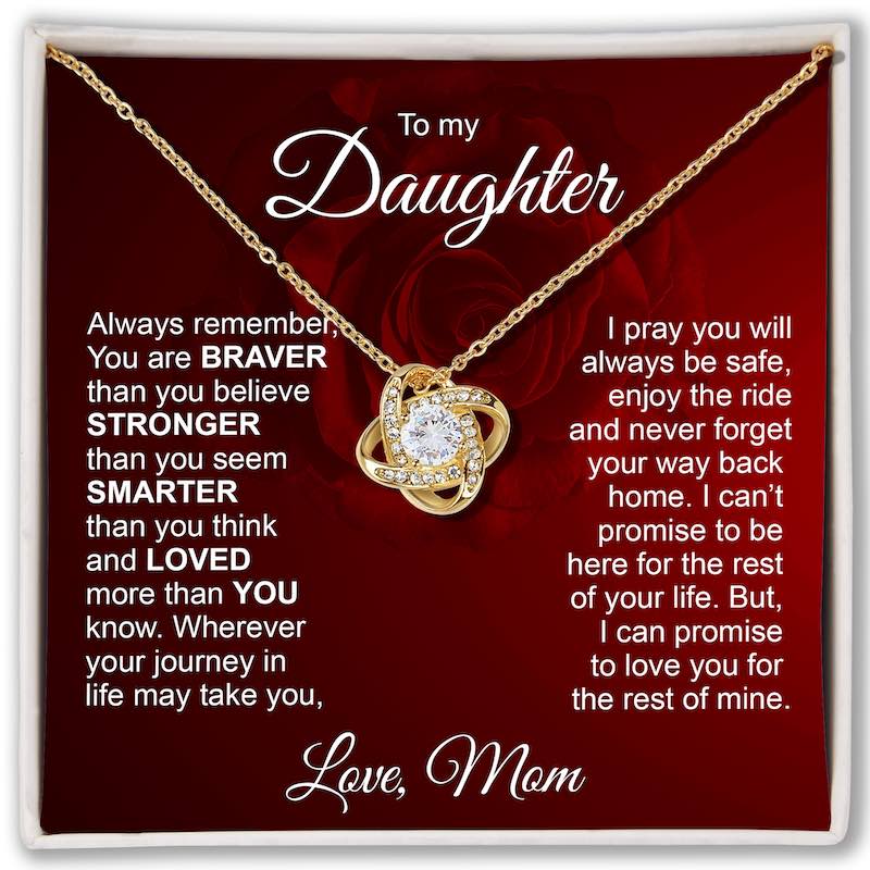 A gold necklace with a heart-shaped pendant set with small clear stones, presented on a red memorial card addressed 'To my Daughter' with sentimental text. The card is framed in white and photographed straight-on.