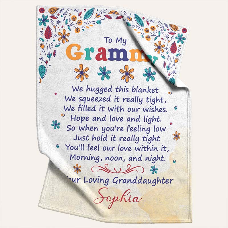 Beige blanket with colorful floral patterns and a touching message, 'To My Grammy' from a loving granddaughter, on a light beige background.