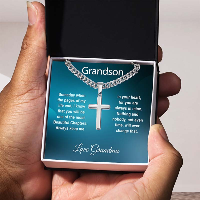 personalised grandson gifts: Silver cross pendant necklace with a heartfelt message card for grandson in a black gift box, held in hand against a neutral background