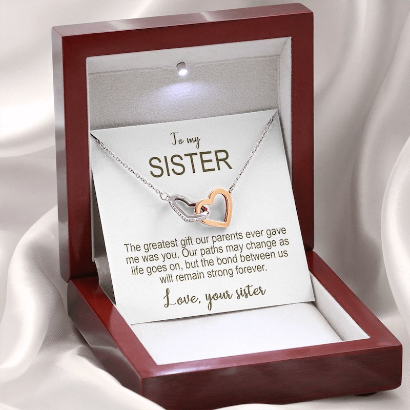 Necklace with interlocking heart pendants in a luxury wooden box with a card for a sister