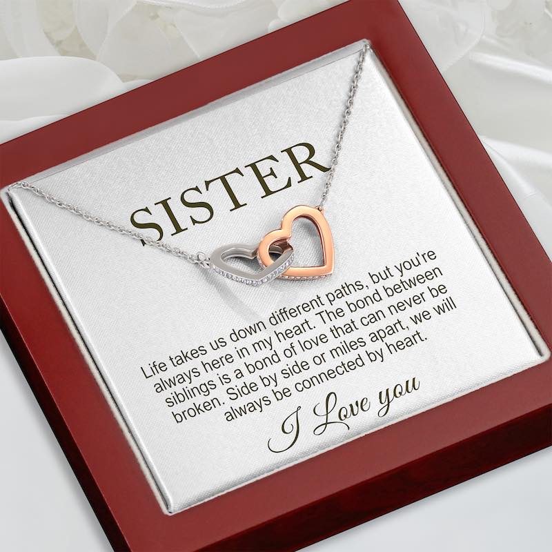 sister gifts for birthday - necklace with interlocking heart pendants on a card for a sister, placed in a red luxury gift box.