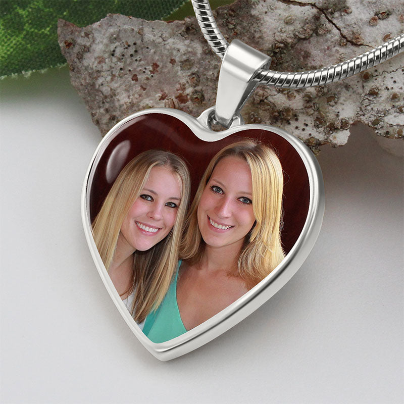 Heart-shaped pendant with a photo of two women on a textured surface