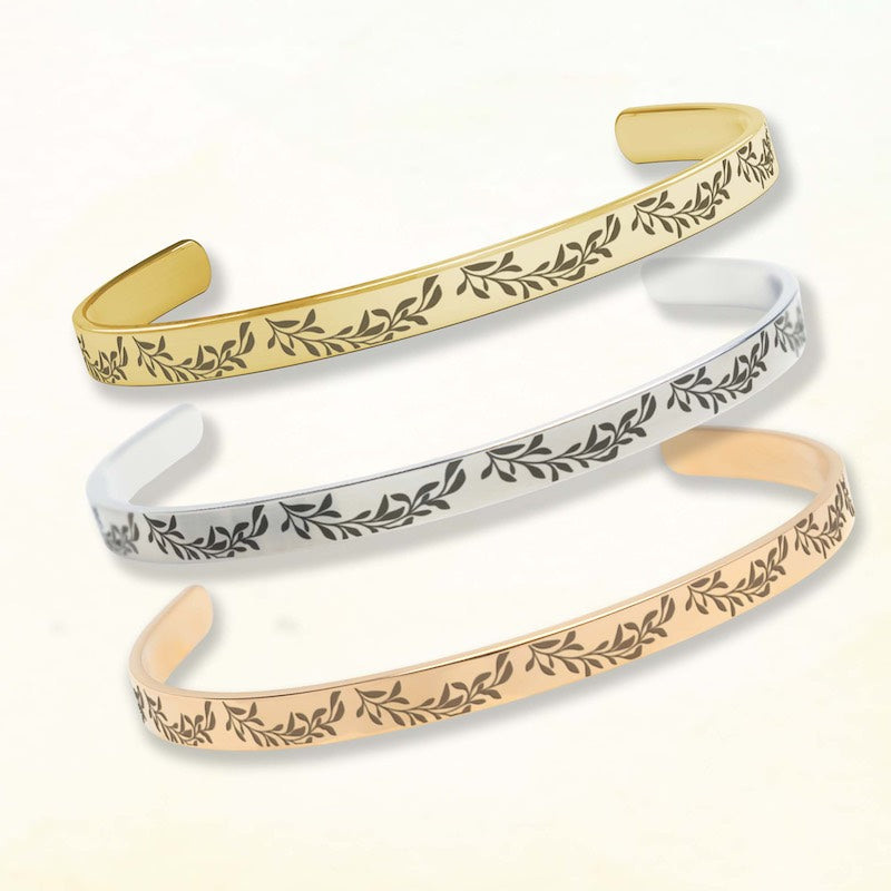 Three gold, silver, and rose gold bangles with leaf patterns on a white background