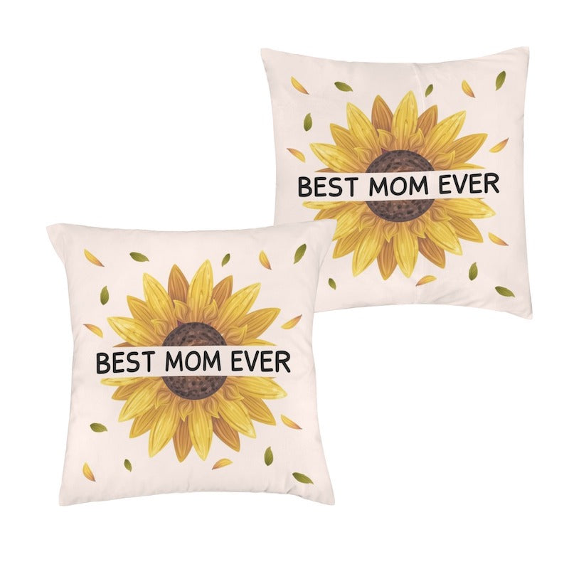 Two square off-white throw pillowcases, each featuring a large yellow sunflower graphic with bold black text reading "BEST MOM EVER" printed across the center.