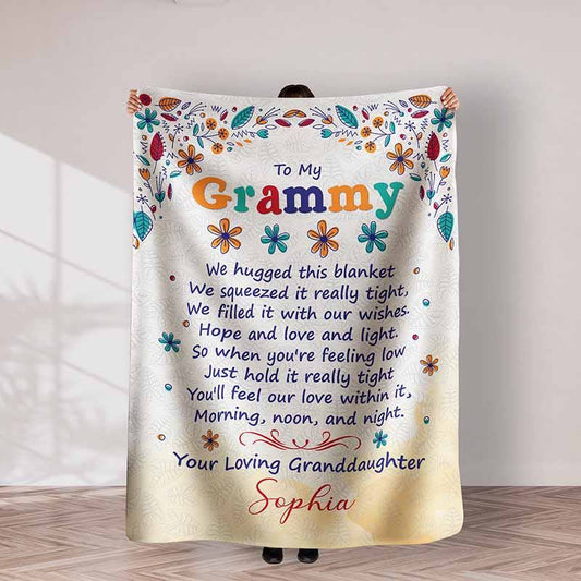 Blanket with personalized message to Grammy, held by a person in a room.