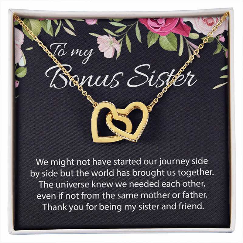 A gold double-heart pendant necklace displayed on a black gift card with floral accents and the words 'To my Bonus Sister,' inside a white gift box with a sentimental message printed below.