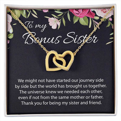 A gold double-heart pendant necklace displayed on a black gift card with floral accents and the words 'To my Bonus Sister,' inside a white gift box with a sentimental message printed below.