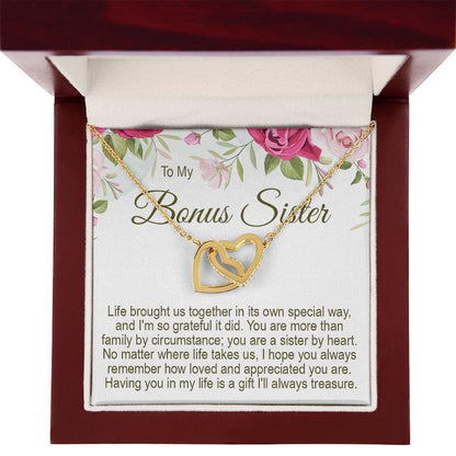 An open mahogany-style wooden gift box displaying a gold interlocking heart necklace secured on a "To My Bonus Sister" floral message card.   
