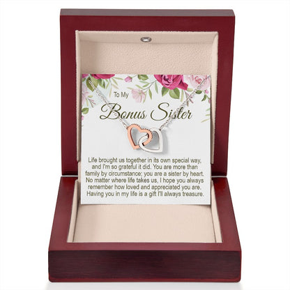 To My Bonus Sister interlocking rose gold and silver heart necklace in an open luxury mahogany-style wooden gift box with a floral message card.   