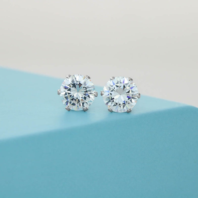 Cubic Zirconia Stud Earrings: Round cubic zirconia stud earrings with silver-tone prong settings displayed on a soft blue surface.
