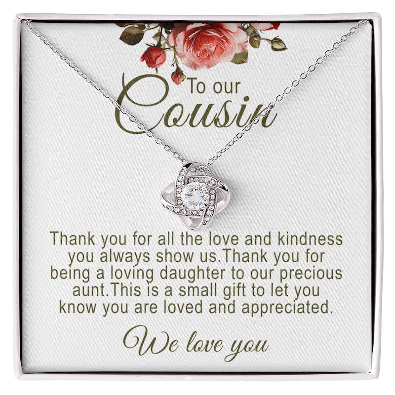 Silver love knot pendant necklace with a round cubic zirconia stone set inside a white gift box with floral artwork and a printed sentimental message titled "To our Cousin".
