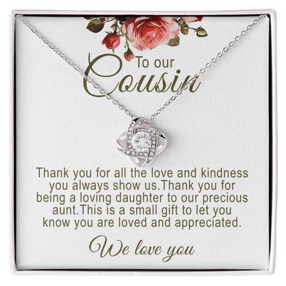 Silver love knot pendant necklace with a round cubic zirconia stone set inside a white gift box with floral artwork and a printed sentimental message titled "To our Cousin".