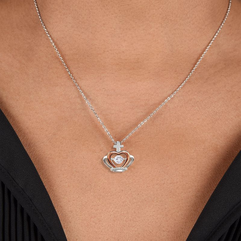 Silver necklace with a crown heart-shaped pendant on a person wearing a black top.