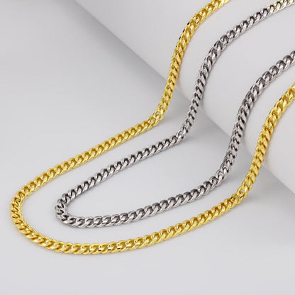 Two cuban link chain necklaces, one gold and one silver, on a light gray background.