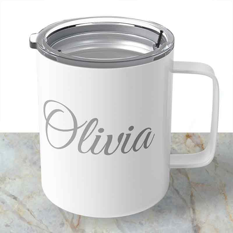 White custom engraved 10 oz insulated stainless steel coffee mug personalized with "Olivia" in script, sitting with its clear lid attached on a light marble surface.   