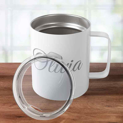 White custom engraved insulated stainless steel coffee mug personalized with "Olivia" in script, sitting on a wooden tabletop with its clear press-in lid leaning against it.
