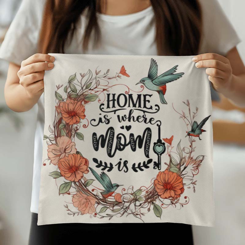 Person holding a custom throw pillow case with floral design and text 'Home is where Mom is'.