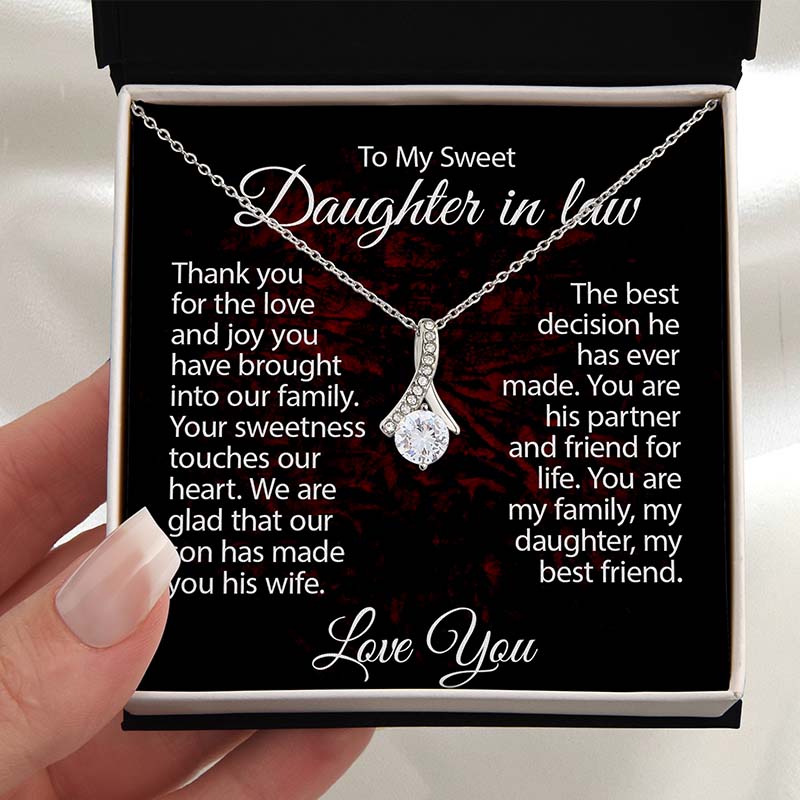 Silver ribbon pendant necklace displayed in a gift box with a heartfelt daughter-in-law message card, held in hand against a soft neutral background.