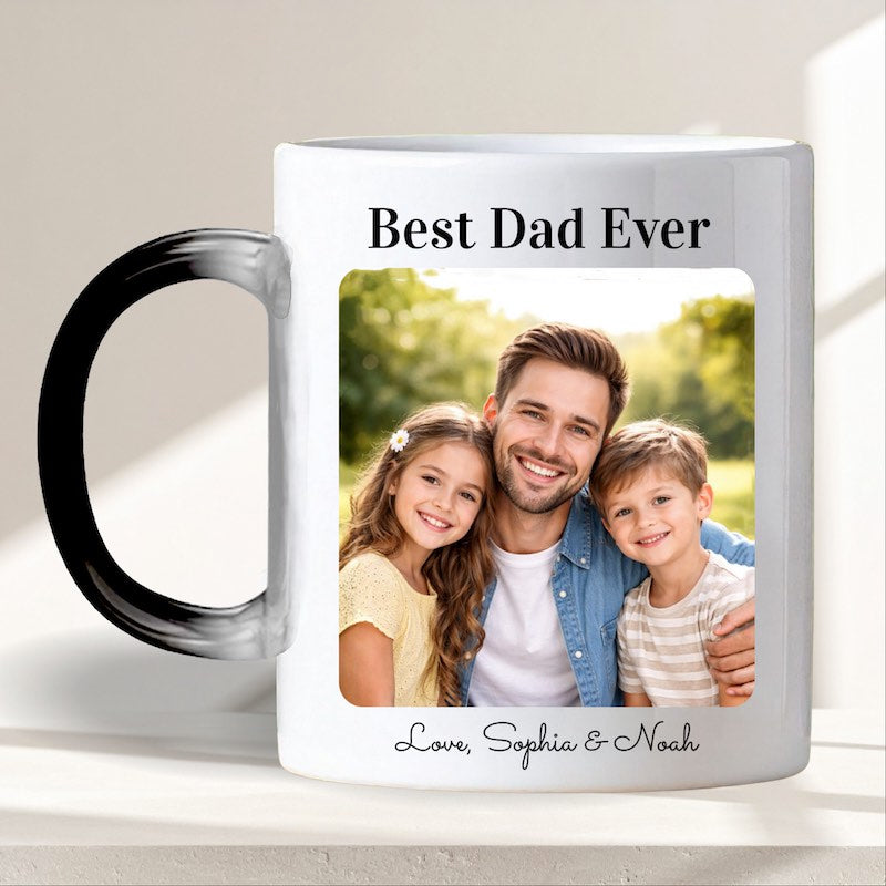 personalized mugs with pictures and text: custom magic mug with a photo of a father and two children, and text 'Best Dad Ever' at the mug top and 'Love Sophia and Noah" at the bottom, on a light surface.