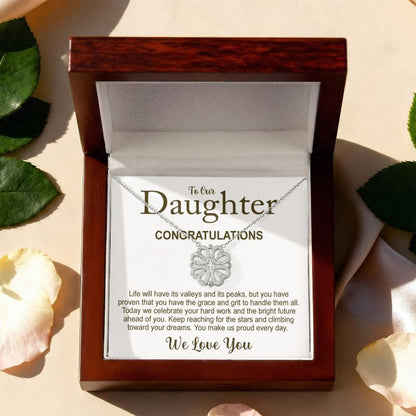 Necklace in a wooden box with a message card for a daughter, surrounded by leaves and flowers.