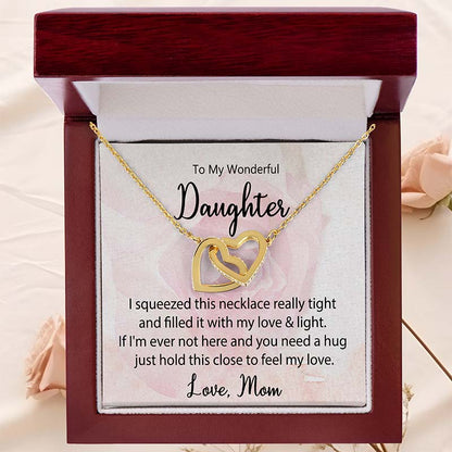 Gold interlocking heart necklace displayed in a luxury mahogany gift box with a heartfelt daughter message card from Mom against a soft blush rose background