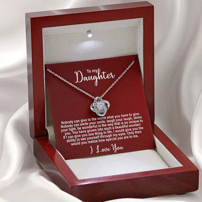 Silver knot necklace with a sentimental message card for a daughter on a red card displayed in a red wooden box against a light silk background.