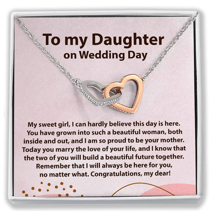 A gift card necklace for a daughter's wedding day, featuring two interlocking heart-shaped pendant links in silver and rose gold, displayed on a pink card with a sentimental message. The card is presented inside a white gift box.