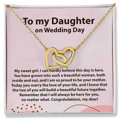 A gold necklace with two interlocking heart pendants displayed on a pink gift card that reads 'To my Daughter on Wedding Day' with a sentimental message below.