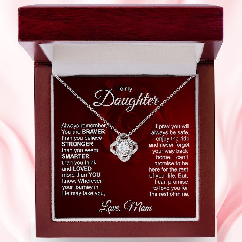 Silver love knot necklace displayed in a mahogany-style luxury gift box with an inspirational message card dedicated "To my Daughter, Love, Mom."   