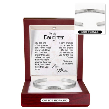 Custom silver cuff bracelet with "Your Text Here" centered on the outer band, presented in an open mahogany gift box with an illuminated interior and a "To My Daughter" card signed "Love, Mom," featuring a top-right inset image demonstrating inside engraving.