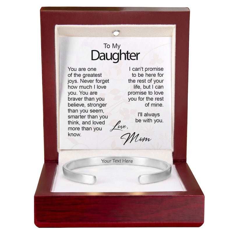Silver cuff bracelet with inside engraving displayed in an open wooden gift box with an illuminated top interior and a printed "To My Daughter" message card signed "Love, Mom."