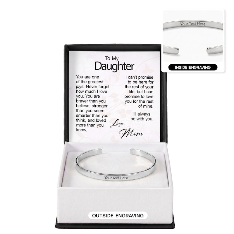 Custom silver cuff bracelet with "Your Text Here" centered on the outer band, displayed in an open gift box in front of a "To My Daughter" sentiment card signed "Love, Mom," featuring a top-right inset image demonstrating inside engraving.