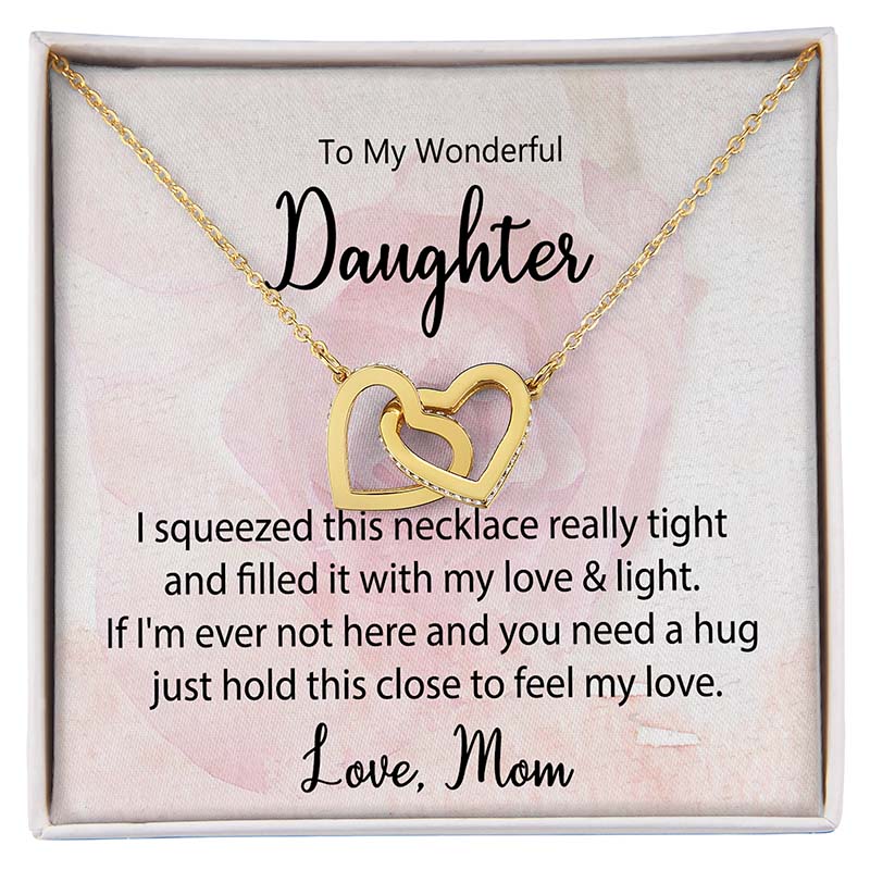 Daughter Interlocking Hearts Necklace: Gold interlocking heart necklace displayed in a gift box with a heartfelt daughter message card from Mom against a soft pink floral background.