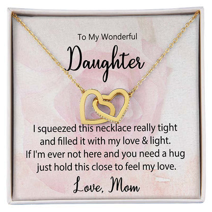 Daughter Interlocking Hearts Necklace: Gold interlocking heart necklace displayed in a gift box with a heartfelt daughter message card from Mom against a soft pink floral background.