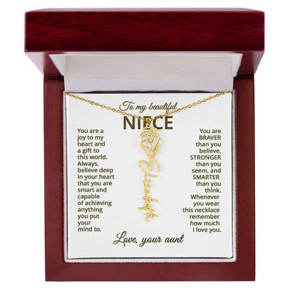 Gold name necklace and narcissus flower pendant on a card with sentimental message for niece on a white background , displayed in a wooden box