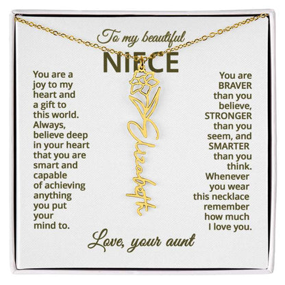 Gold name necklace and narcissus flower pendant on a card with sentimental message for niece on a white background , displayed in a white box.