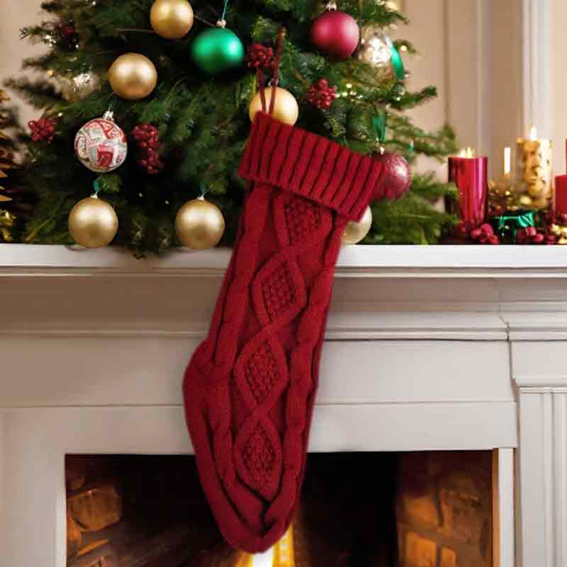 Red knit Christmas stocking hanging on a white fireplace mantle beneath a decorated Christmas tree with colorful ornaments.