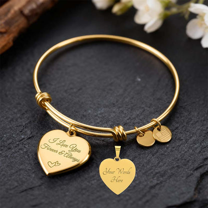 Gold engraved bracelet with heart-shaped charms on a dark surface with flowers in the background