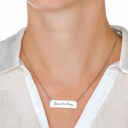 A close-up of a person's neck and upper chest wearing a silver-toned chain necklace with a rectangular silver nameplate engraved with the names 'Jason & Mary'.
