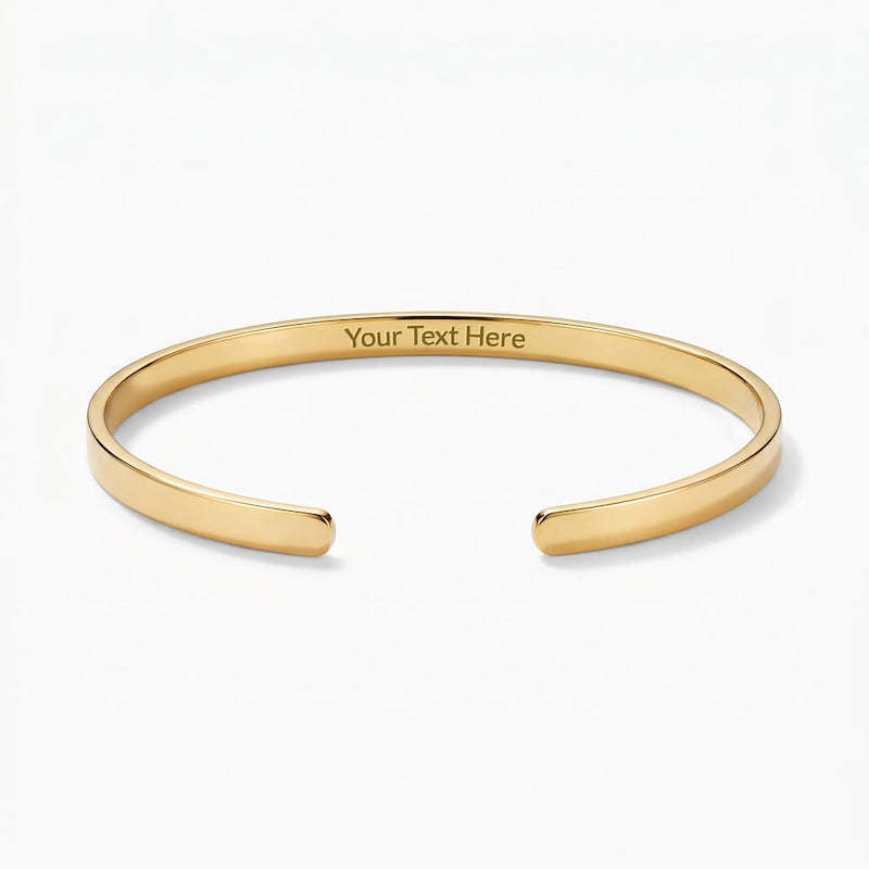 Gold engraved cuff bracelet with sample text reading "Your Text Here" centered on the inside band, displayed on a plain white background.