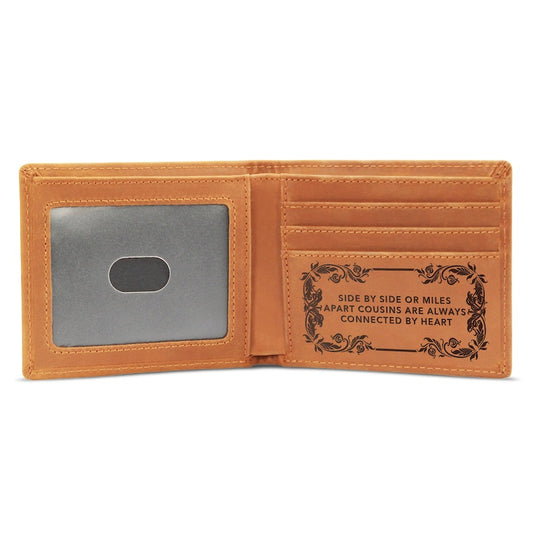 An open tan leather wallet featuring an ID window on the left and card slots with an engraved message frame reading "Side by side or miles apart cousins are always connected by heart" on the right.   