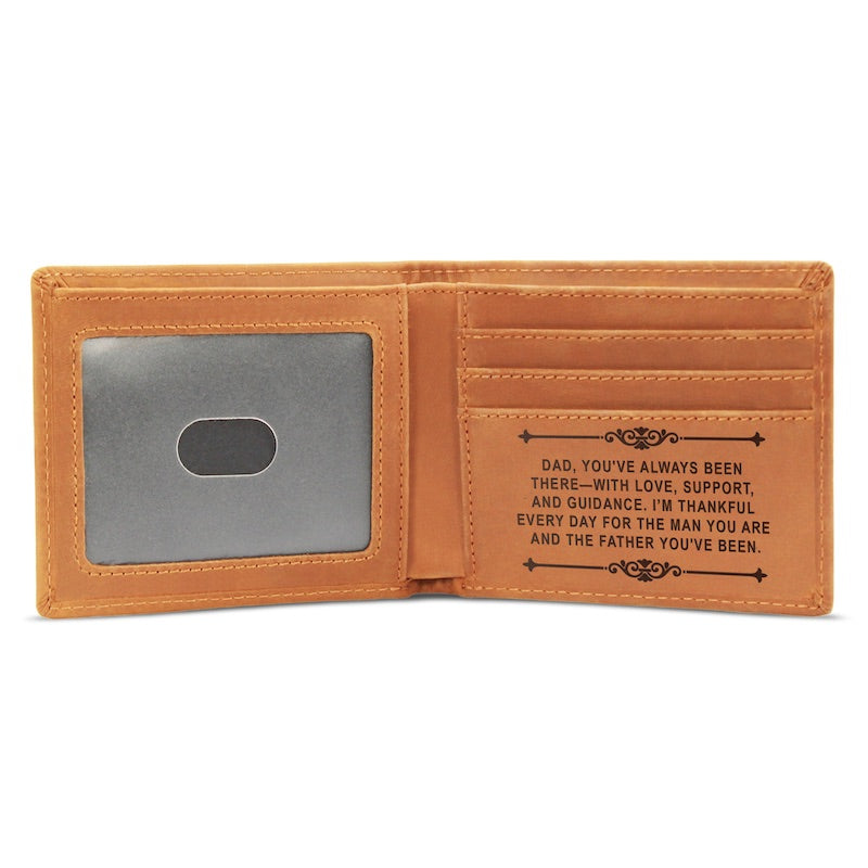Inside view of an open tan bifold leather wallet against a plain white background, showing a clear ID window on the left and card compartments laser-engraved with a message of gratitude for Dad on the right.   