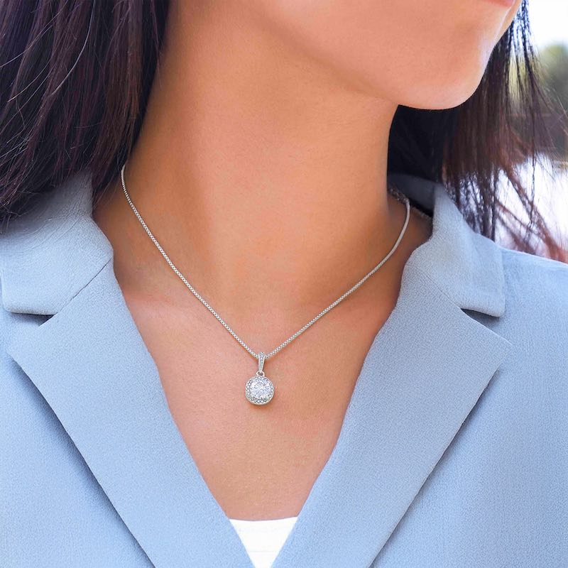 Silver Cubic Zirconia necklace with a round pendant worn by a person in a light blue blazer.