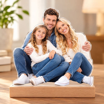 Custom acrylic family photo cutout plaque resting on a natural wooden base in a warm home setting.