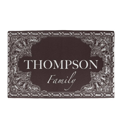 Personalized dark brown doormat customized with your family name, featuring ornate white scrollwork corner designs and border details. - Gifts For Family Online