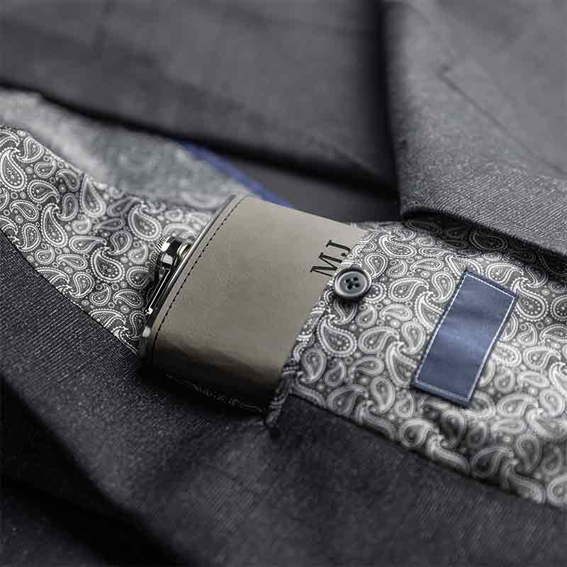 Gray custom engraved stainless steel flask tucked inside a gray suit jacket pocket.