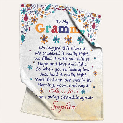 Beige blanket with colorful floral patterns and a touching message, 'To My Grammy' from a loving granddaughter, on a light beige background.