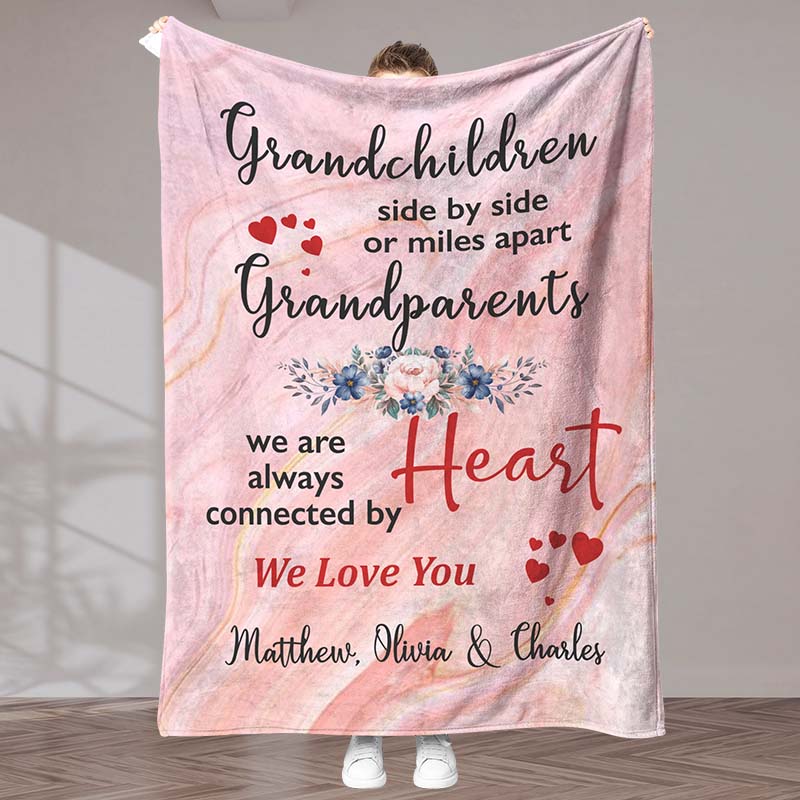 A pink blanket with a meaningful message for grandparents from grandchildren, with a heart and floral design, held by a person