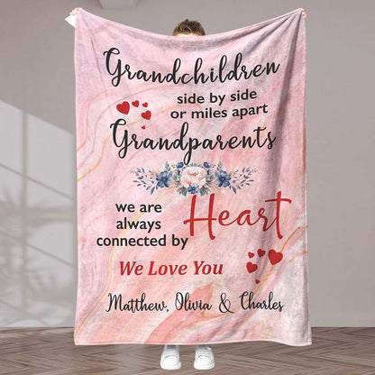 A pink blanket with a meaningful message for grandparents from grandchildren, with a heart and floral design, held by a person